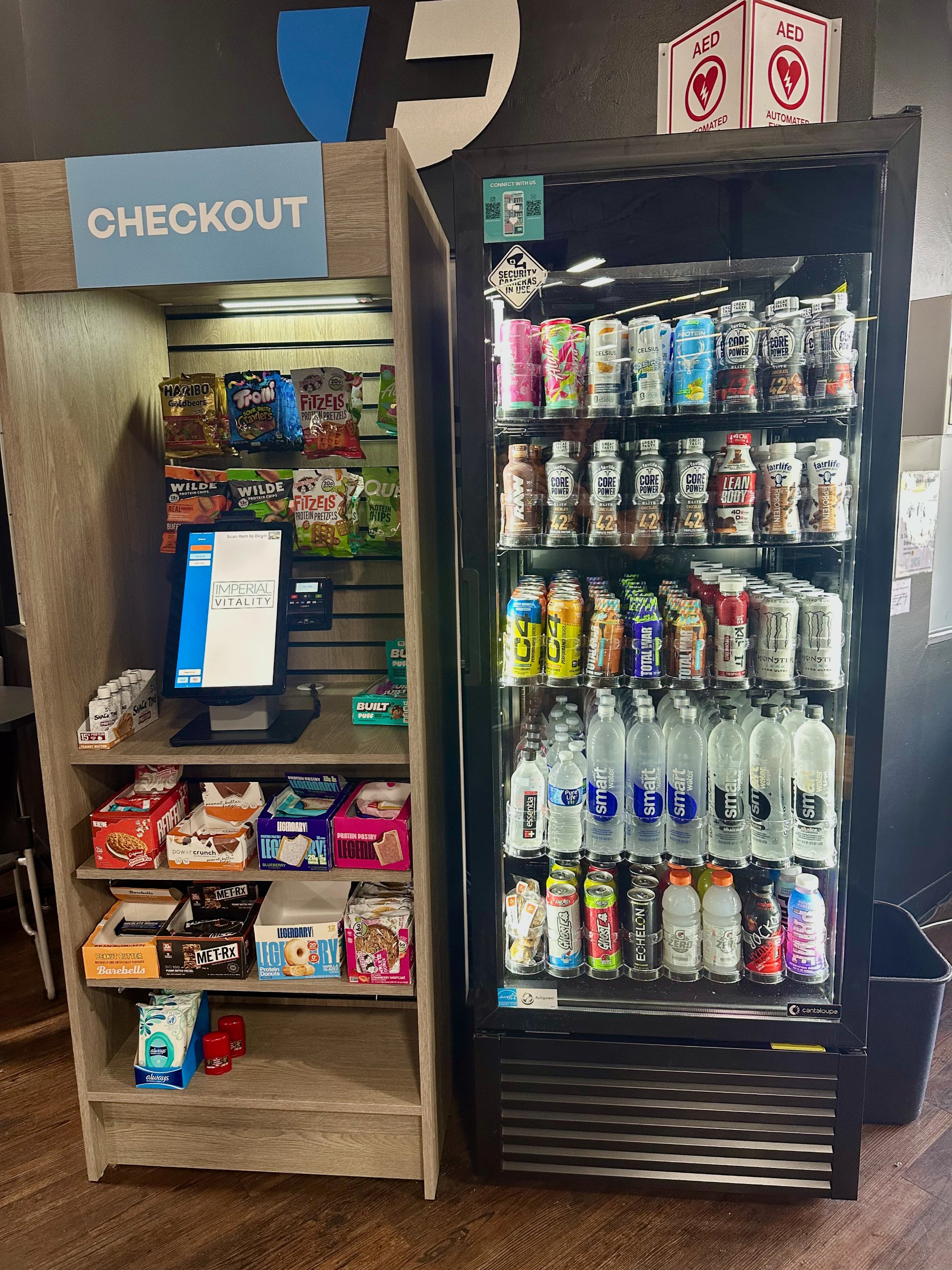 Imperial Vitality setup &mdash; checkout kiosk with snacks beside a cooler stocked with drinks